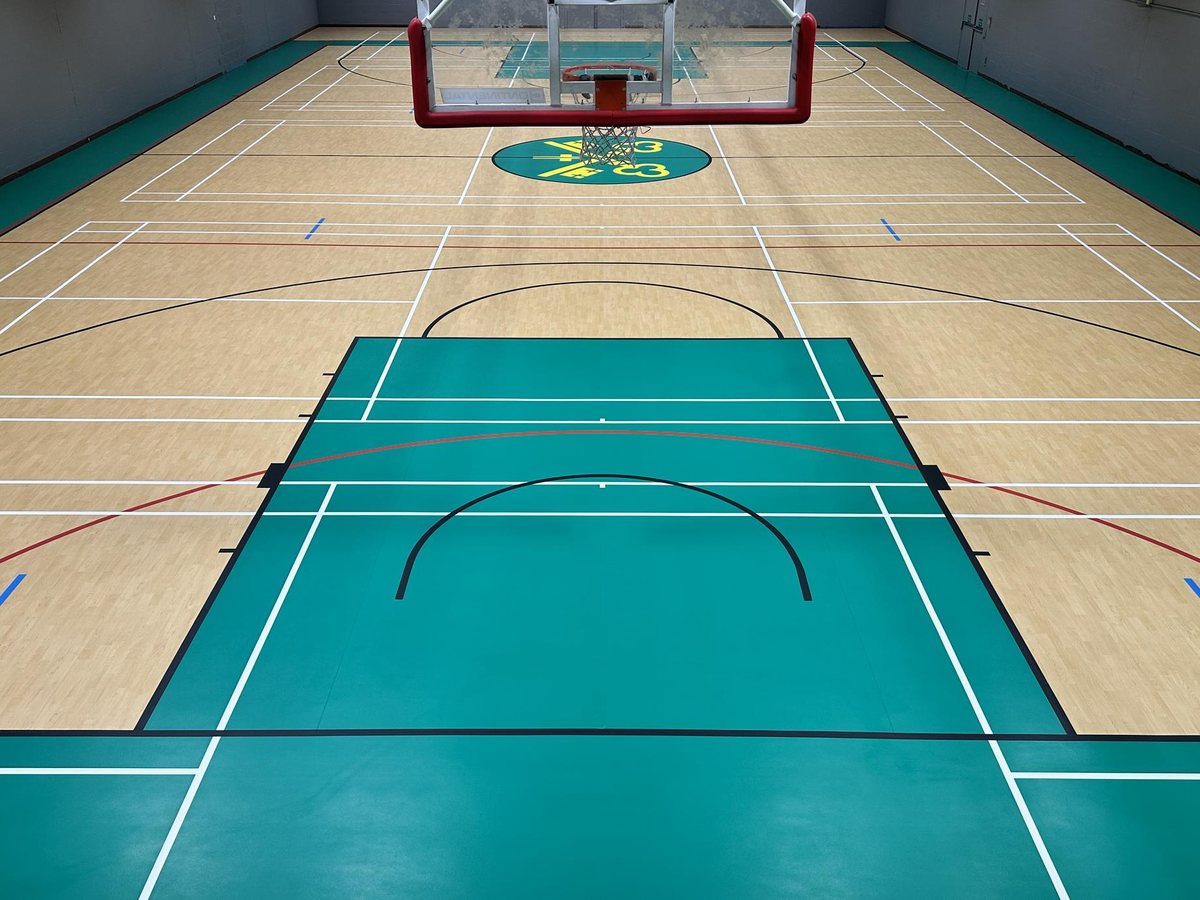 Sports hall with newly marked multi-sport courts on a wood-effect and green floor