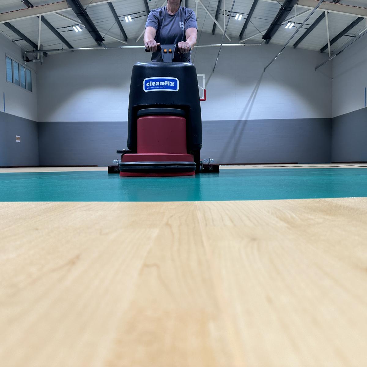 Cleaning a newly installed sports floor with a scrubber dryer before marking