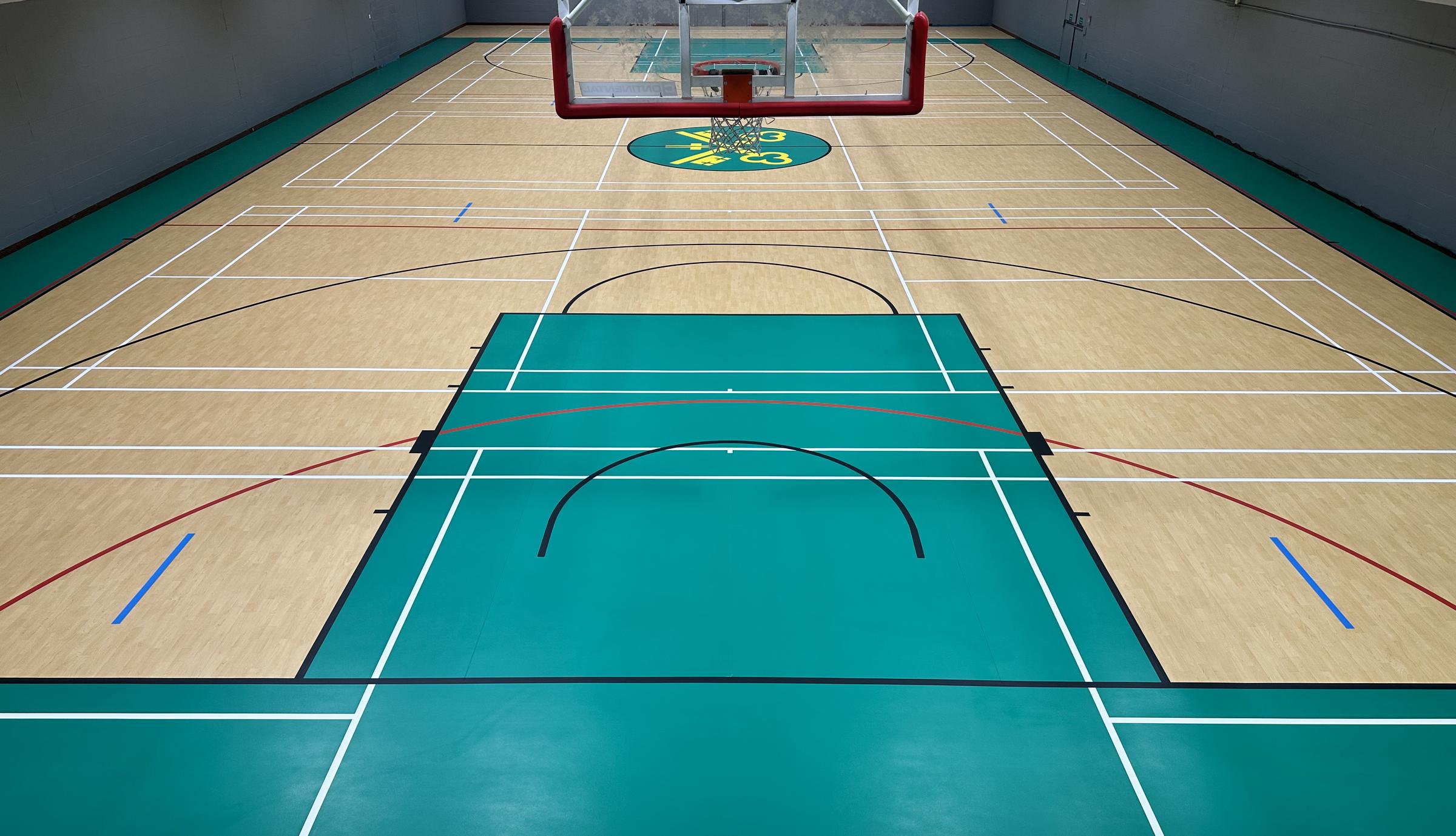 Sports hall with newly marked multi-sport courts on a wood-effect and green floor